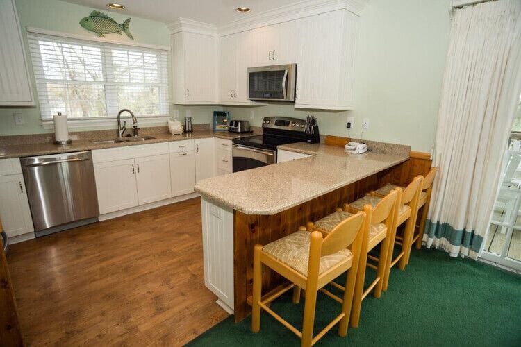 Your fully equipped kitchen features granite counters, stainless appliances, and a spacious island with seating for four—perfect for preparing home-cooked meals or gathering over morning coffee together.