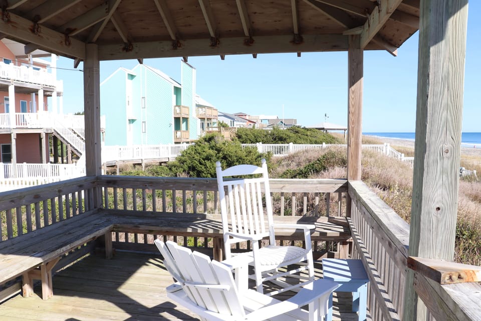 Relax on your covered deck with coastal views, where white Adirondack chairs invite you to unwind with ocean breezes.