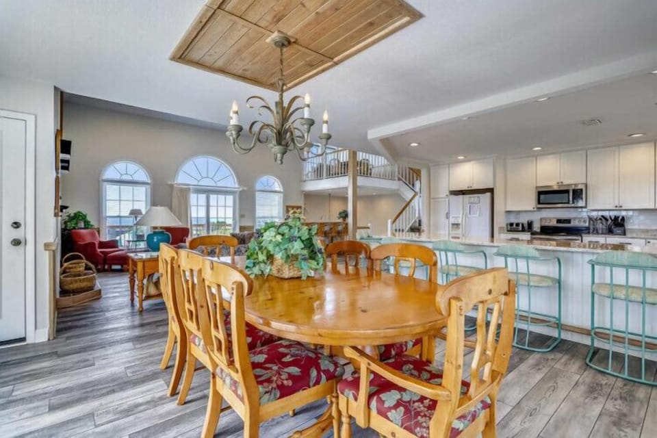 Step into your coastal-inspired living space where soaring ceilings and arched windows flood the open-plan layout with natural light, connecting dining, living, and kitchen areas for effortless entertaining and relaxation.