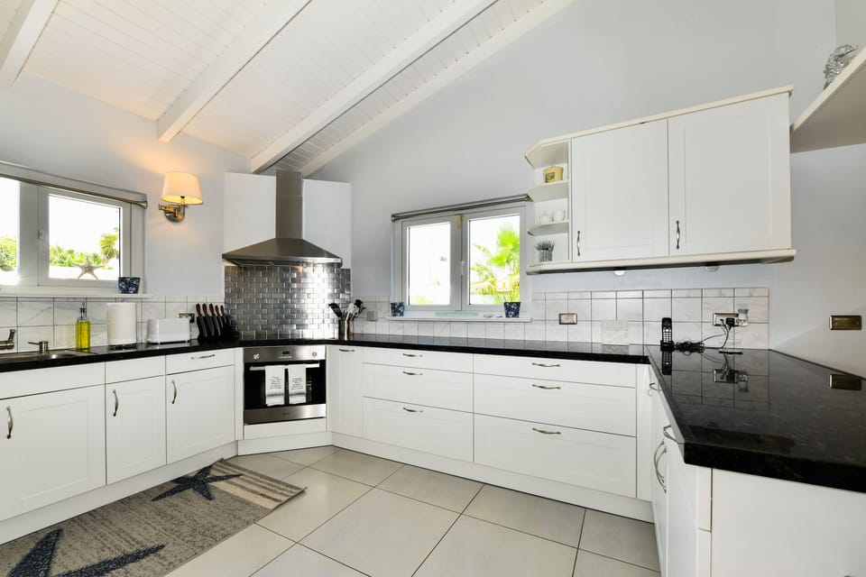 Fully equipped kitchen looks out on to living area, lanai and pool