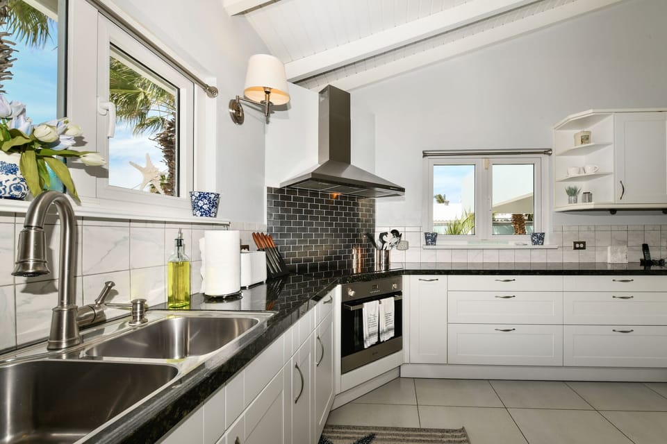 Fully equipped kitchen, looks out into living area, lanai and pool.