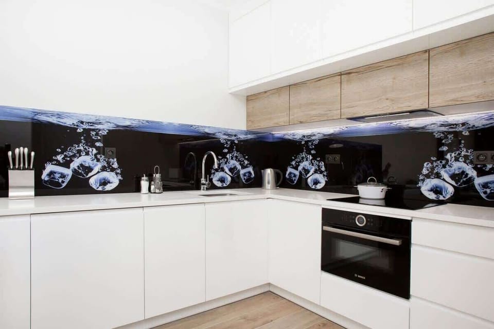 A sleek kitchen with white cabinetry, dark artwork in minimalist design, and white countertops for a contrasting look.