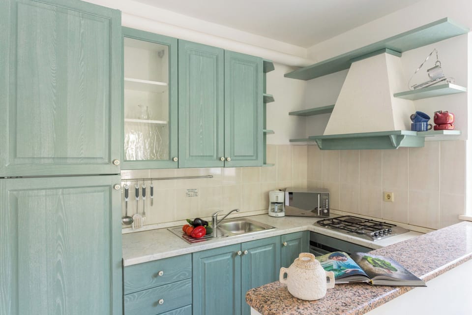 Prepare a delightful meal in one of the villa's well-equipped kitchens, featuring charming teal-colored cabinetry and modern appliances.
