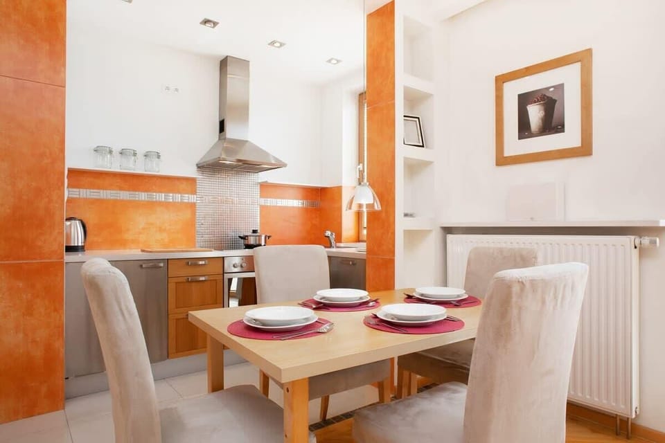 A close-up of the dining table set for a meal, with red accents adding a pop of color against the warm wooden tones.