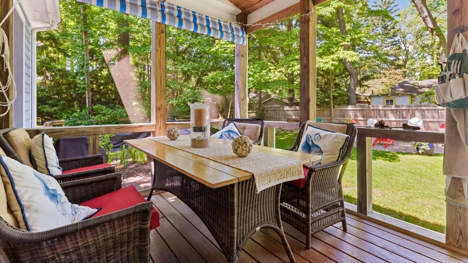 Screened porch with lush garden views and comfortable seating