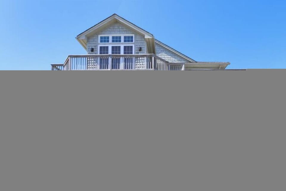 A coastal vacation home elevated on sturdy pilings, featuring multiple wraparound decks and balconies that maximize your views and outdoor enjoyment.