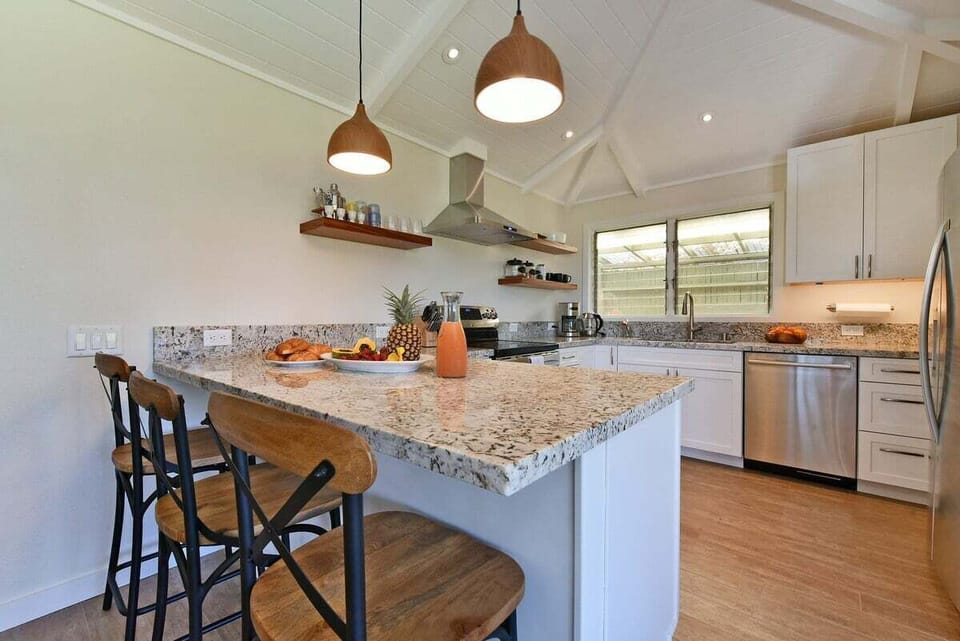 Modern kitchen with bar seating, pendant lights, and open layout.