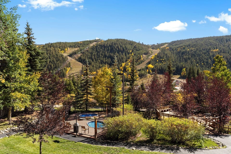 Mountain resort with heated pool surrounded by autumn foliage and ski slopes.