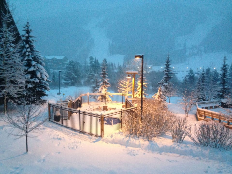 Snow-covered outdoor hot tub surrounded by winter forest, creating a magical alpine retreat setting.