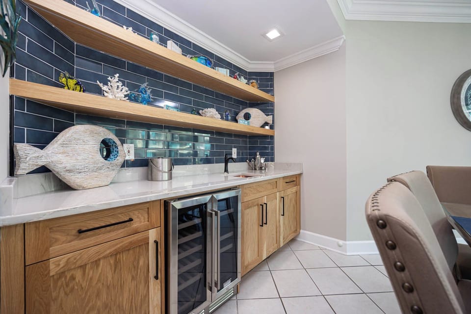 Grab a chilled bottle of wine from the cooler at the wet bar while admiring the charming coastal decor and vibrant accents