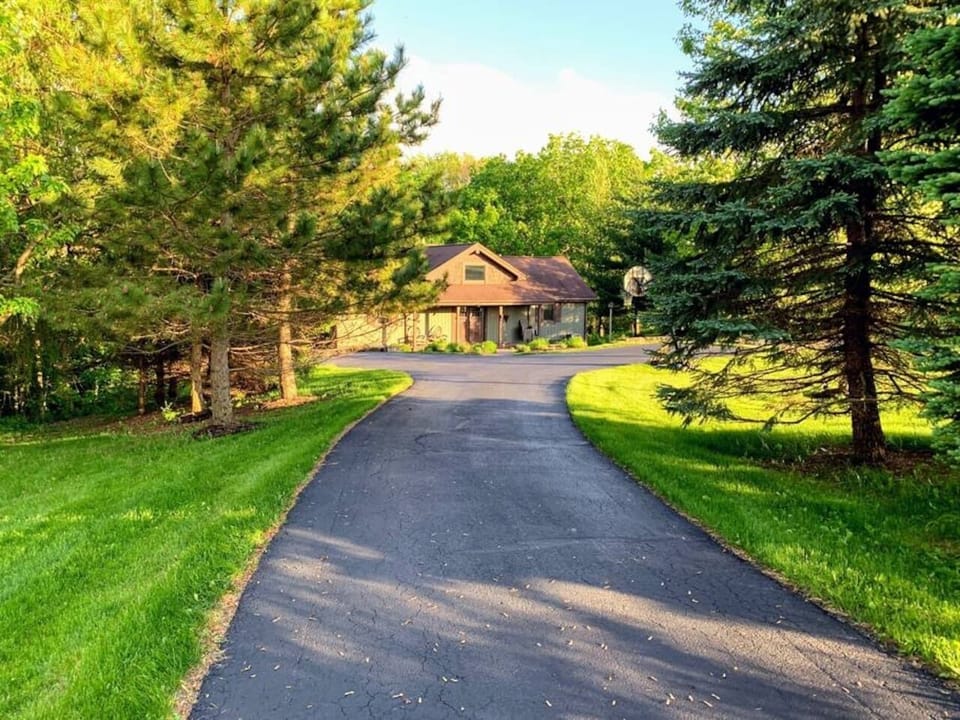 This inviting property features a curved driveway, vibrant green landscaping, and a basketball hoop — ideal for families and guests seeking a peaceful stay.