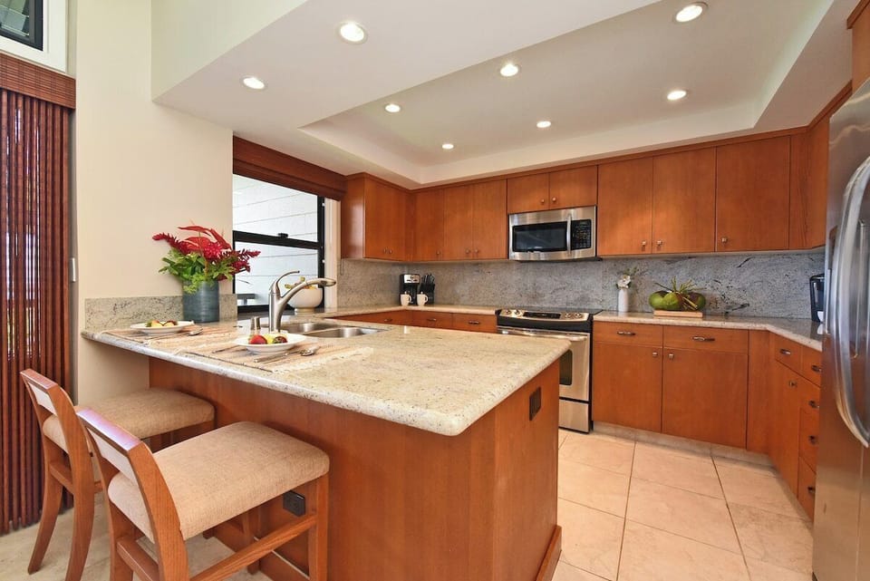 Fully equipped remodeled kitchen with granite countertops, modern appliances, and breakfast bar seating for casual meals.