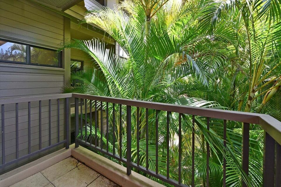 Shaded bedroom lanai with railing and lush greenery views, perfect for quiet mornings or evening relaxation.