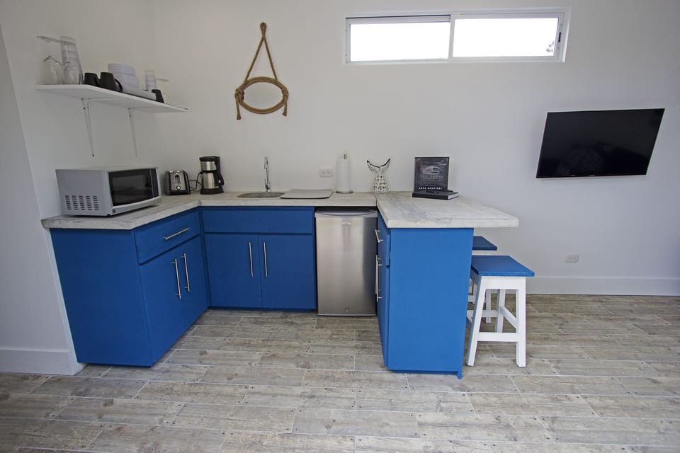 Kitchen with mini fridge, microwave, coffee maker, toaster and hot plate.