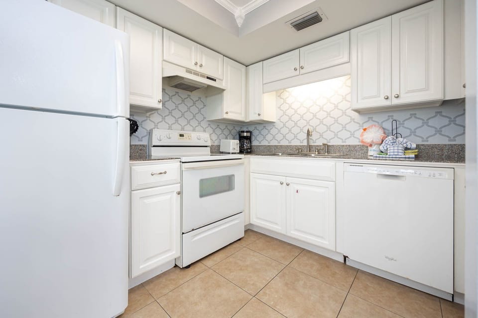 Bright kitchen featuring white cabinetry, granite countertops, and a coffee maker for your morning brew