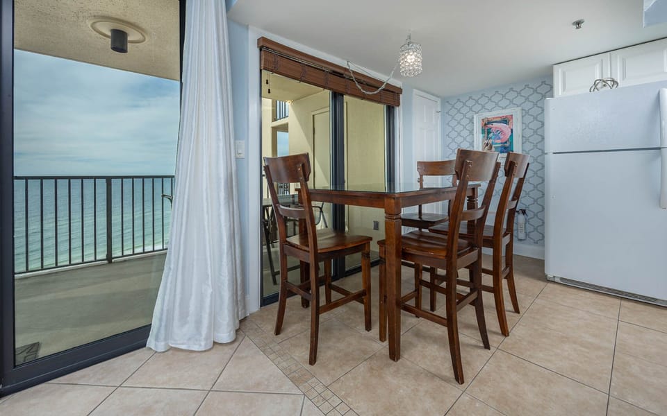 Bright dining area with a wooden table, high chairs, and a breathtaking view of the tranquil waters beyond the balcony