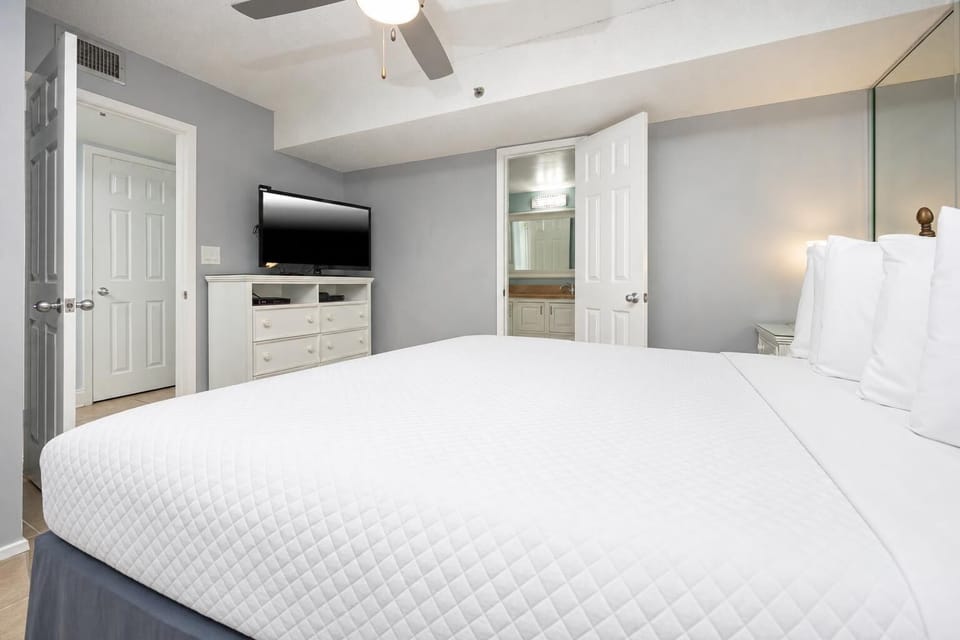 Bright and inviting bedroom featuring a cozy king bed, flat-screen TV, and an ensuite bathroom for added convenience