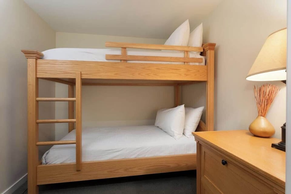 Bedroom 2 - Bunk room ideal for families or groups with wood furnishings  
- Comfortable bedding and warm lighting create a cozy space  
- Interior den room without window designed for quiet rest