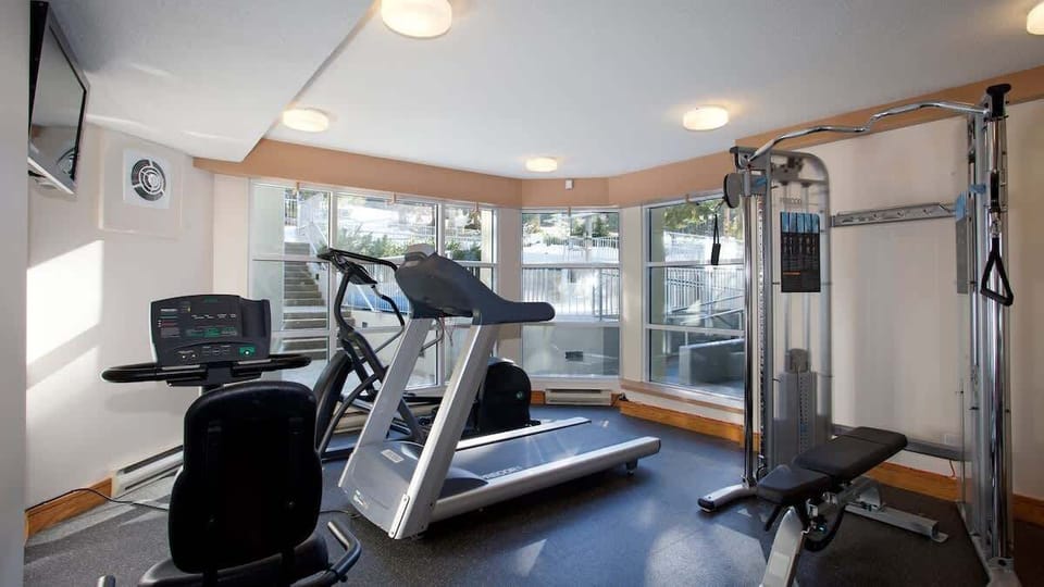 - Fully equipped fitness room with treadmill, weights, and scenic views  
- Stay active during your Whistler getaway with modern gym amenities  
- Bright workout space overlooking alpine surroundings and pool area  