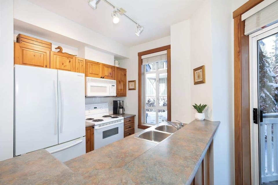 - Fully equipped kitchen featuring wooden cabinetry and modern appliances  
- Bright open layout offers easy access to balcony and dining space  
- Perfect spot to prepare hearty meals after a day of Whistler adventure 