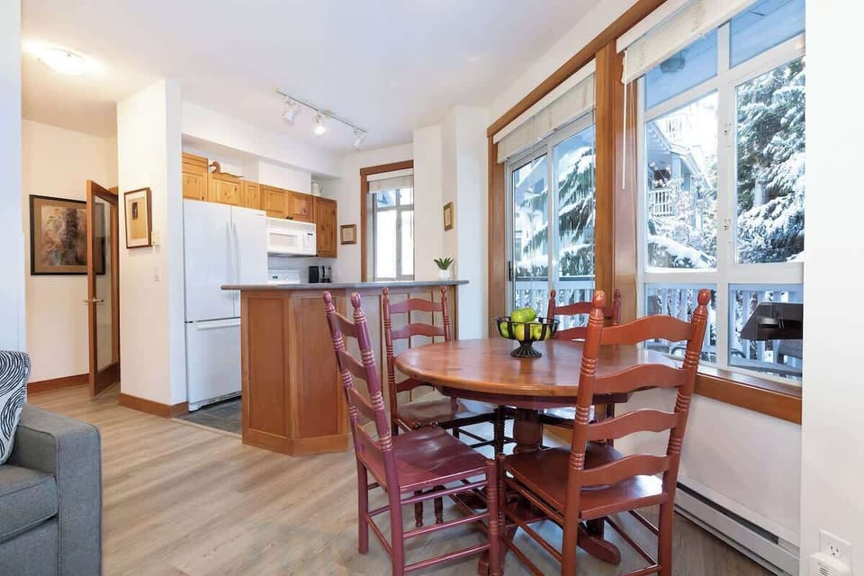 - Spacious dining nook filled with natural light and forest views all around  
- Warm wooden tones and alpine charm create a welcoming dining experience  
- Gather for memorable meals after a fun day exploring Whistler’s slopes 