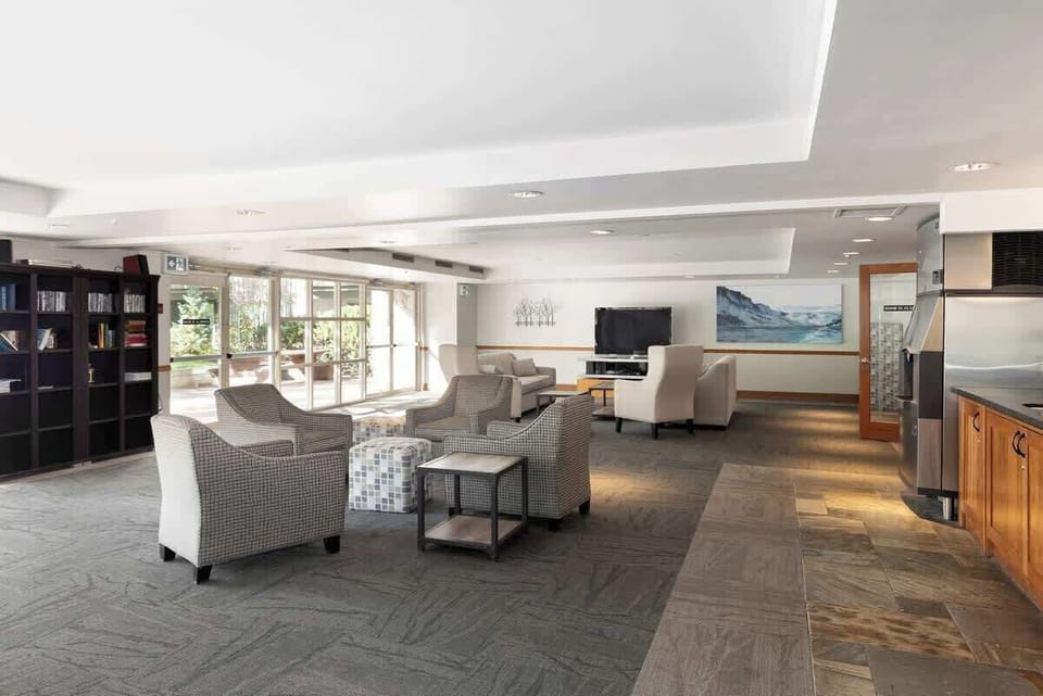- Spacious lounge with soft seating, TV, and reading area for guests  
- Ideal for relaxing, socializing, or enjoying quiet downtime indoors  
- Bright common space blending comfort and mountain charm 