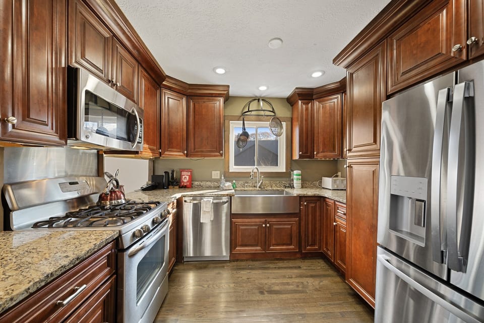 Kitchen with Custom Cabinetry, Stainless Farm Style Sink, Granite Counters, and Stainless Appliances
