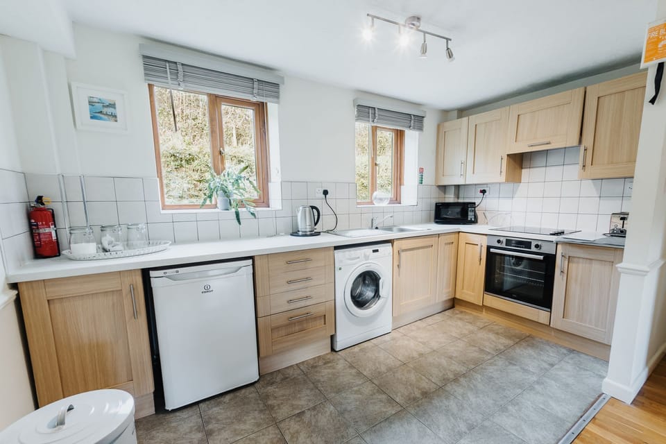 The kitchen including a fridge and washing machine - Nobbys Cottage