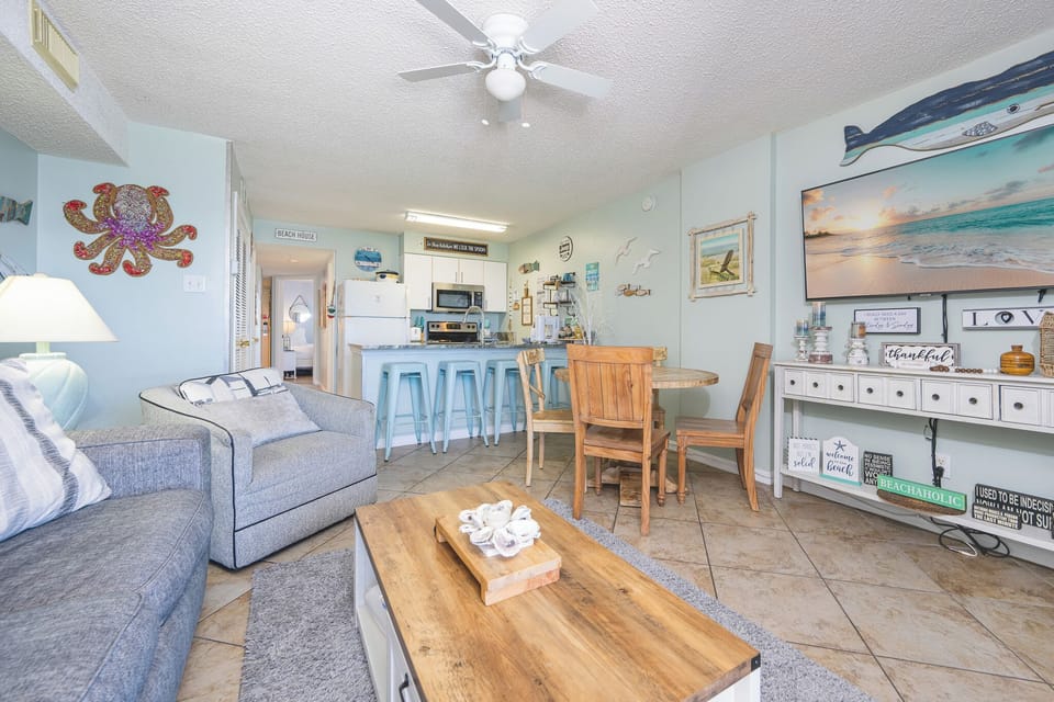 This cozy living area features a large TV, beach-themed decor, and a welcoming atmosphere perfect for relaxation