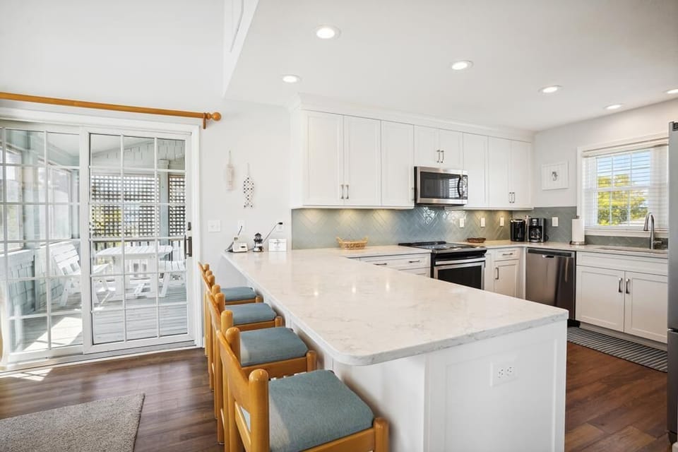 Your bright, fully-equipped kitchen invites you to prepare meals together with gleaming white counters, modern appliances, and a spacious island with seating for casual dining or morning coffee.