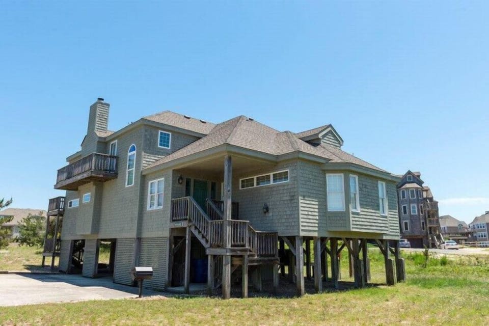 A spacious coastal home elevated on stilts, offering proximity to the beach and ocean breezes with ample outdoor space surrounding the property.