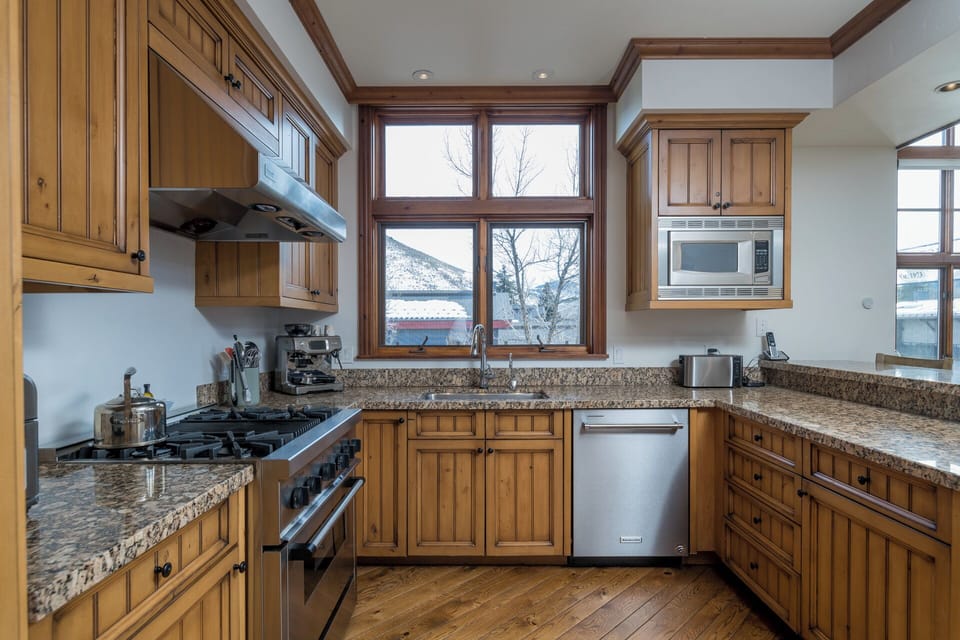 Your dream kitchen features rich wooden cabinets, granite counters, and stainless appliances, with mountain views through charming windows.