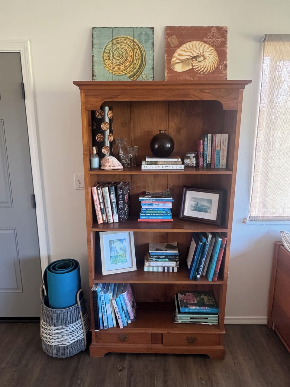 Teak bookshelf with lots of reading materials. Also yoga mat