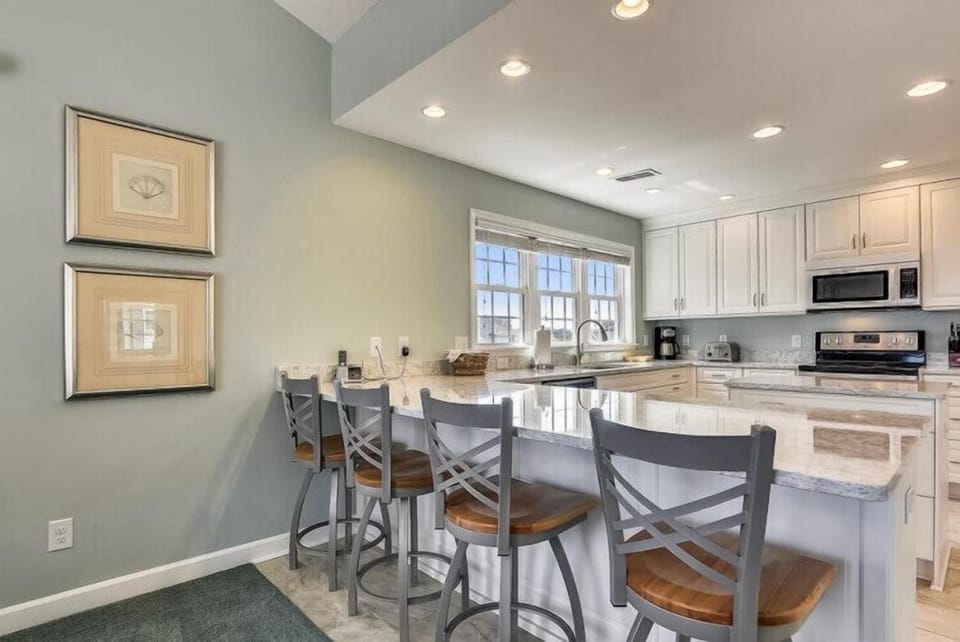 You'll love gathering at this open breakfast bar, perfect for morning coffee or casual meals. The bright, airy kitchen offers coastal charm and everything you need to feel at home.