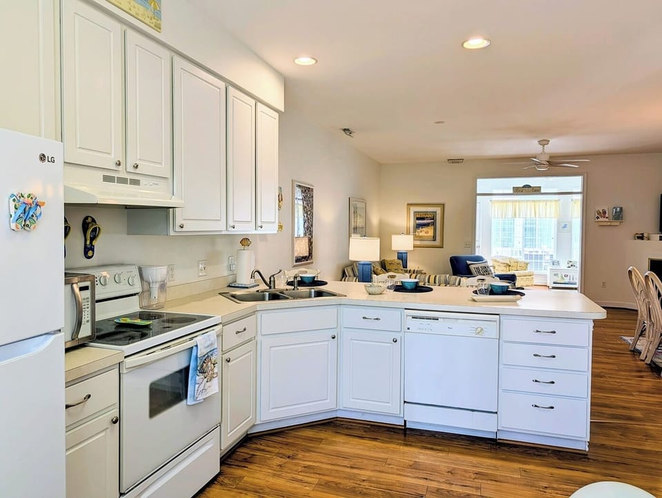 618 Driftwood Court - Modern White Kitchen - The kitchen boasts crisp white cabinetry, modern appliances, and a wrap-around counter that serves as a convenient breakfast bar. Recessed lighting and a window over the sink keep the workspace bright and efficient.