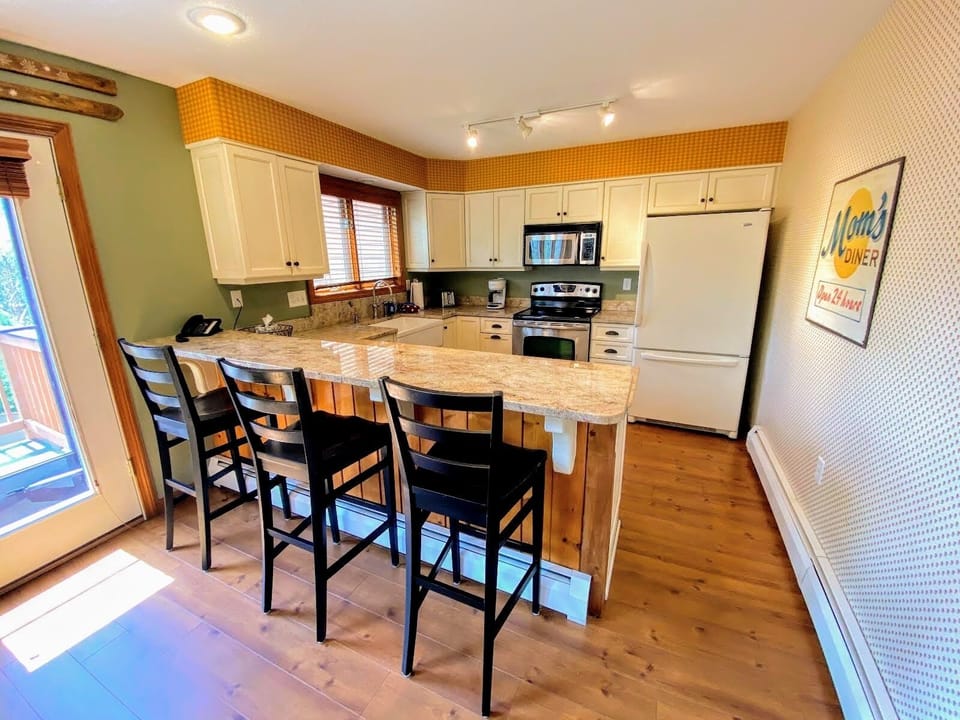 The well equipped kitchen has granite countertops, a drip coffee maker, and breakfast bar seating for four.