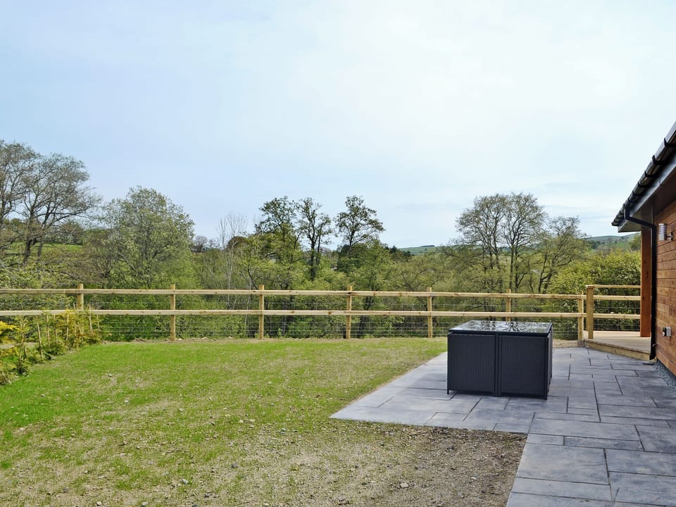 Enclosed, lawned garden | Woodland Lodge - Bryncoch Holidays, Hundred House, near Builth Wells