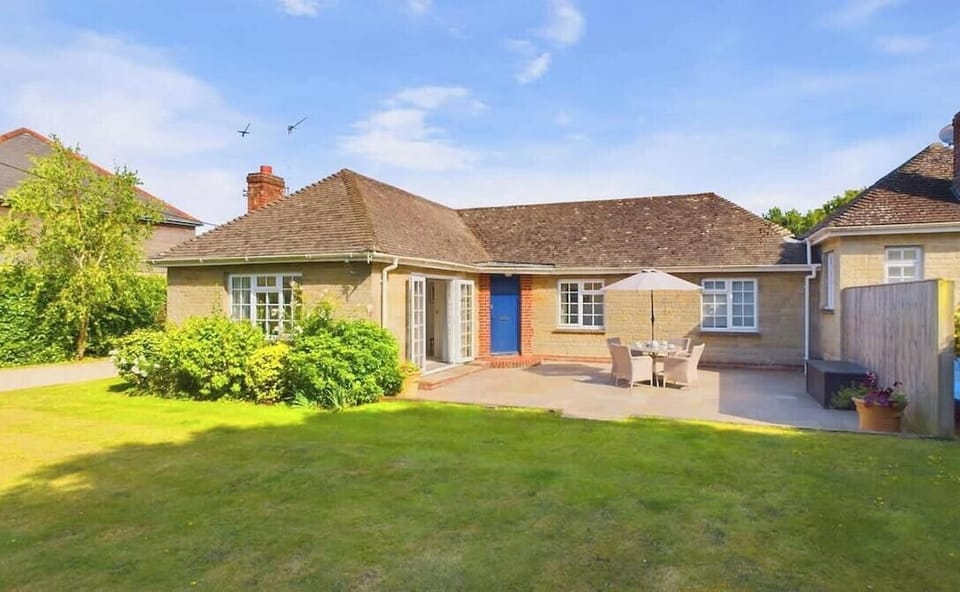 Front exterior of White Roses coastal holiday bungalow in Bembridge with patio area and outdoor table and chairs.