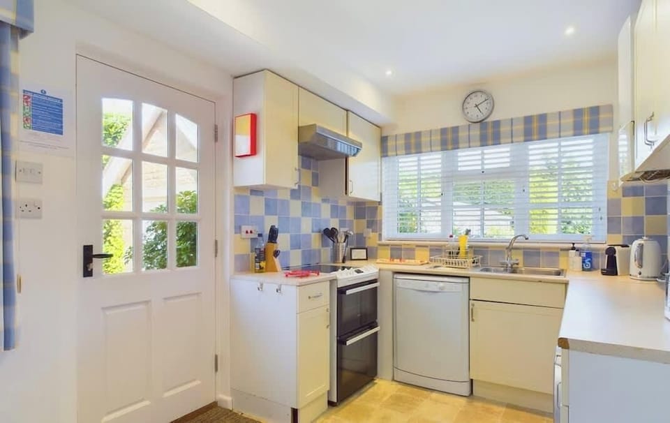 Well-equipped kitchen and dining area at White Roses with appliances, worktops and table seating for four.
