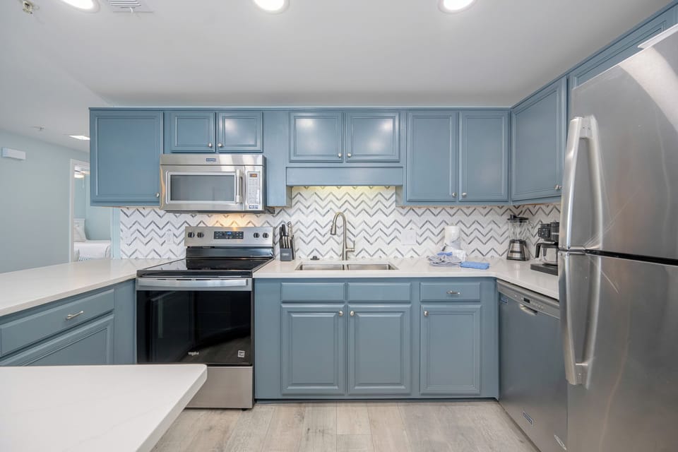 Soft light shines on the kitchen's blue cabinets as the Keurig ready for your morning brew awaits you