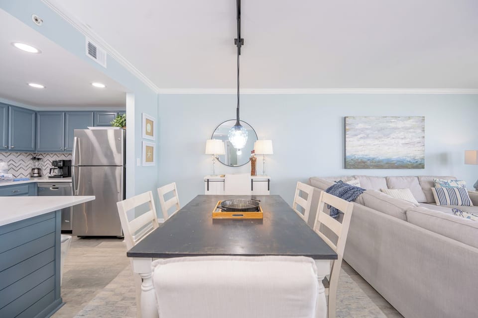 A serene dining area invites you to enjoy meals and conversations surrounded by soft blue walls and coastal art
