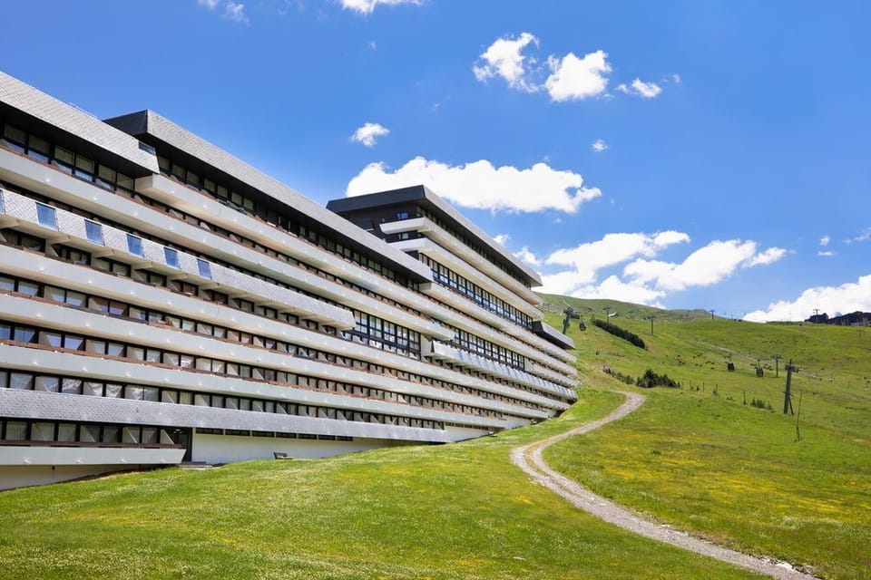 The Le Brelin building in summer, green slopes replacing snow and the mountains just as commanding.