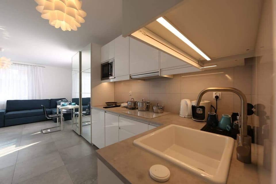 A closer look at the kitchen area in warm lighting, showing the modern fixtures and compact design suitable for studio living.