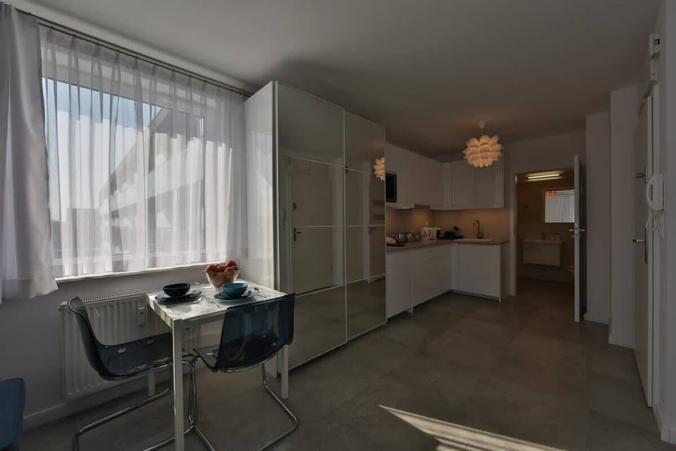 Another view of the studio living space, featuring a small round dining table with chairs, perfect for a cozy meal or workspace.