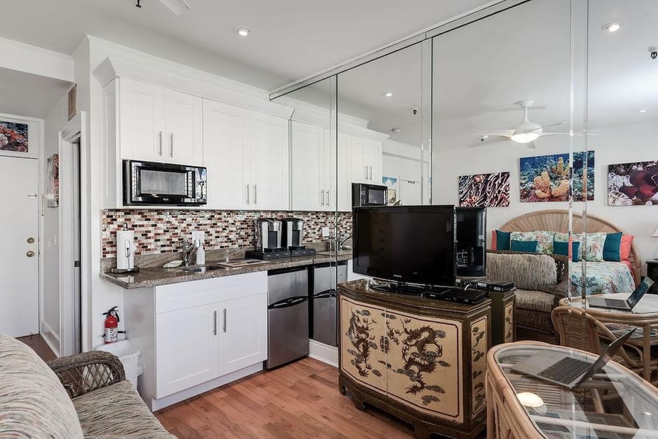 Kitchenette with a Toaster oven, microwave, mini fridge, Keurig coffee makes, glasses, plates, and cutlery.