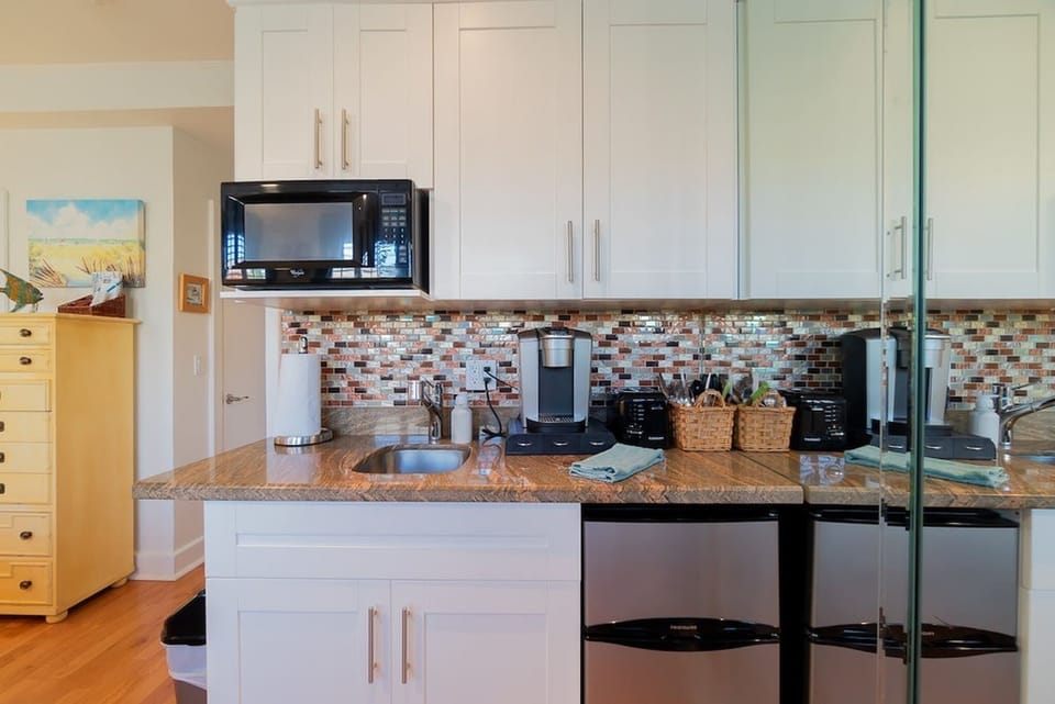 Kitchenette, microwave, mini fridge, Keurig coffee maker, glasses, plates, and cutlery. 