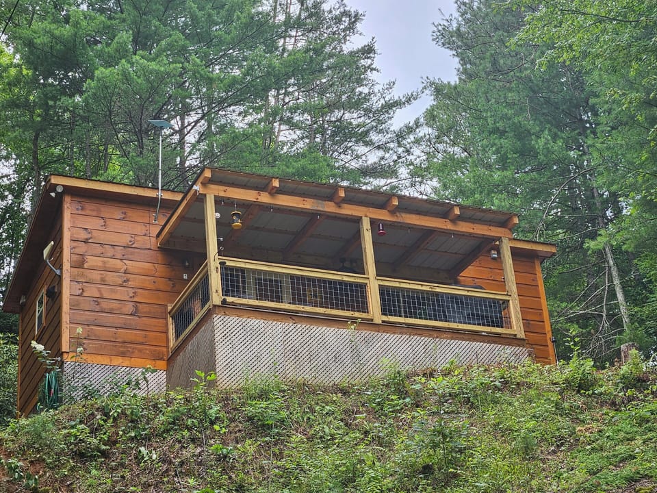 Cabin on the hill in summer, with new covered deck added in 2024.