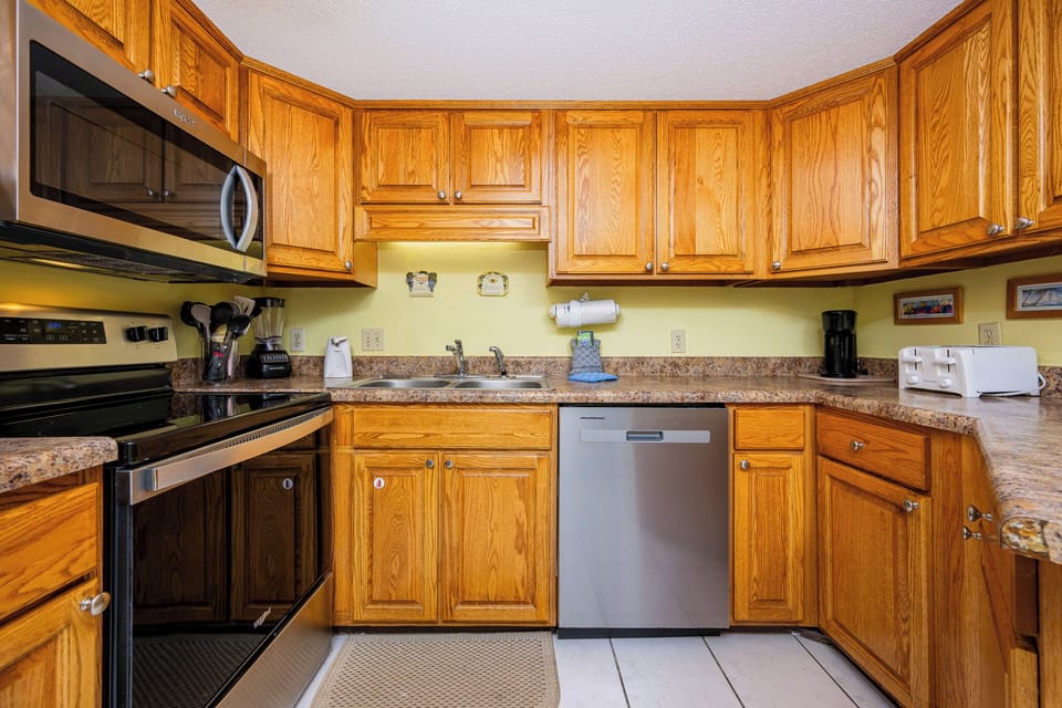 The kitchen features warm wood cabinetry, granite countertops, and stainless appliances, creating a welcoming space