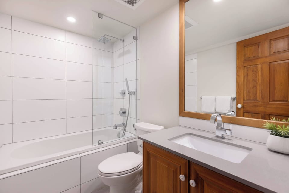 - Modern bathroom with glass-enclosed tub and sleek tiled walls  
- Warm wood cabinetry blends beautifully with neutral finishes  
- Refresh after mountain adventures in this clean, calming space  
