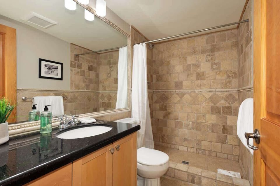 - Modern bathroom with granite vanity and spacious walk-in shower  
- Neutral tile design adds warmth and mountain character  
- Clean stylish and convenient after-ski refresh spot  